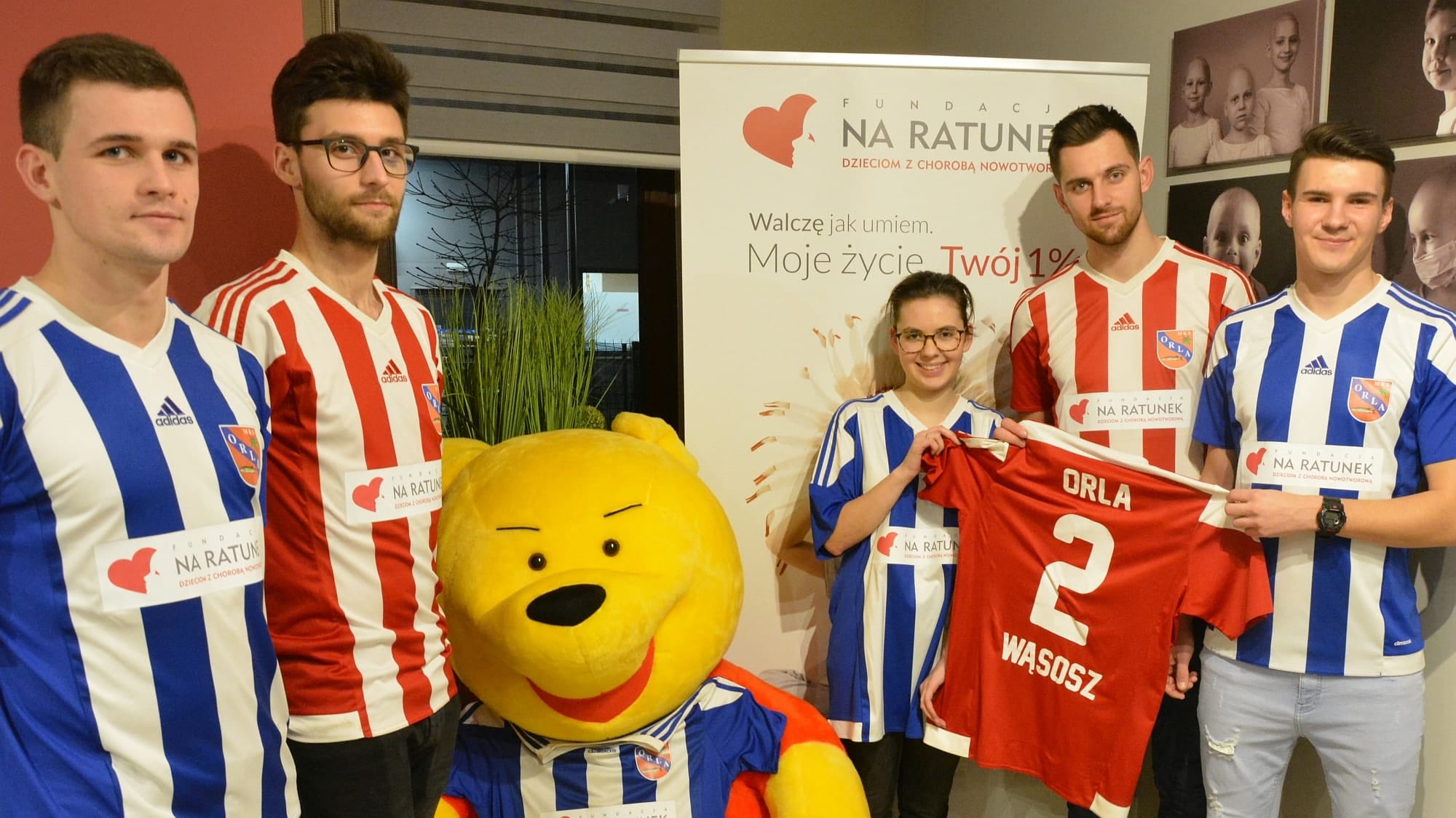 Orla Wąsosz z logo Fundacji Na Ratunek Dzieciom z Chorobą Nowotworową