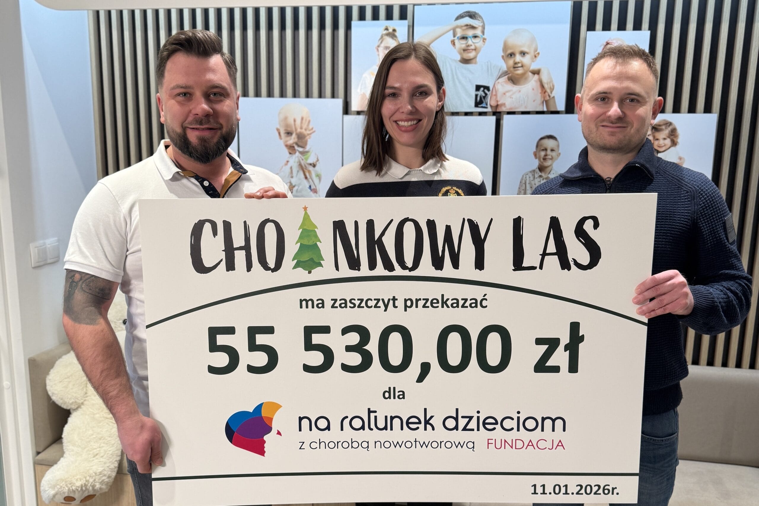 Trzy osoby trzymające duży symboliczny czek